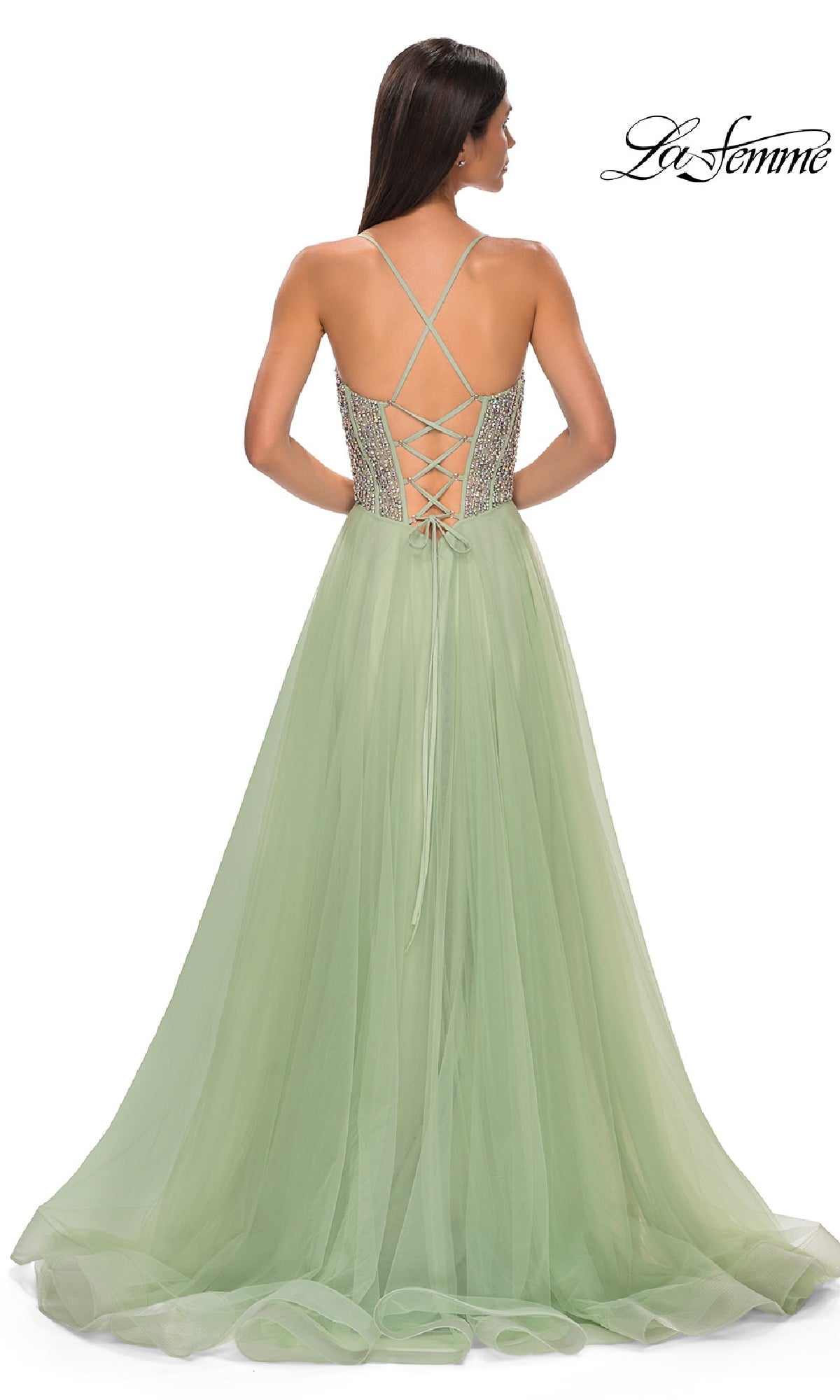 A woman is wearing the Beaded-Corset Long Prom Dress La Femme 32703, featuring a light green tulle skirt, fitted bodice with lace-up open back, thin shoulder straps, and an elegant floor-length a-line silhouette.